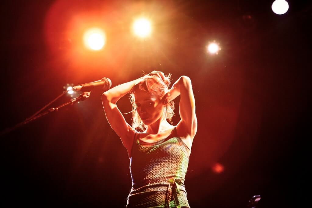 Fiona Apple terlihat sedang memperbaiki rambutnya saat sedang tampil di panggung